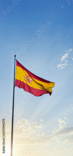 Flag of Spain waving at the top of a post with a bottom of sunny blue sky