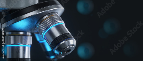 Detailed close-up of modern microscope objective lenses with blue neon illumination on a dark background.