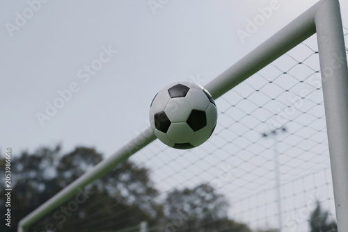Classic soccer ball hitting the crossbar or flying into the goal gate post on a cloudy day. Concept of football match, scoring a goal, missing target, game over, tournament, and outdoor sports.