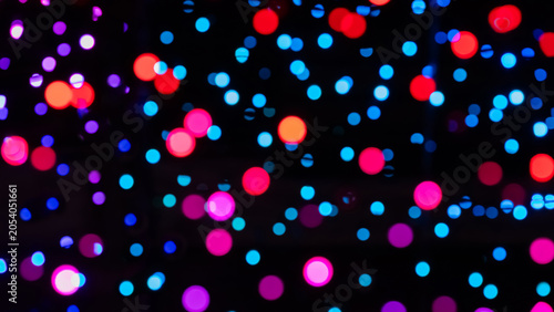 Abstract background of pink, purple, and blue bokeh lights against a dark can...