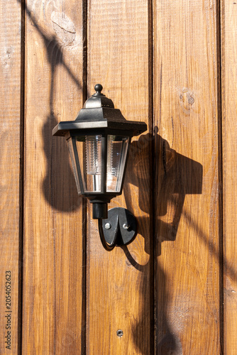 An iron lantern hangs on the wall of a wooden house, space for text