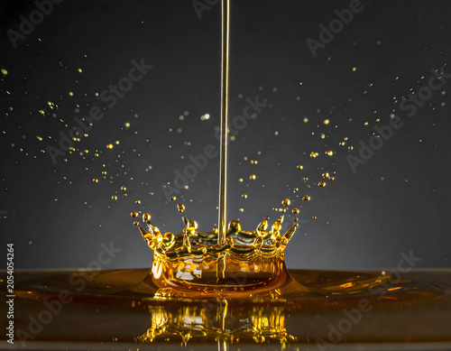 Liquid Gold Motion: Gold liquid oil pour creates energetic crown splash and burst of droplet. Dynamic movement expresses dramatic power of fluid