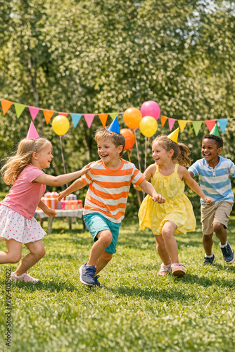 A lively children's outdoor party with cheerful kids running and holding balloons.
