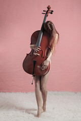 Musician holding cello in artistic nude portrait on pink background