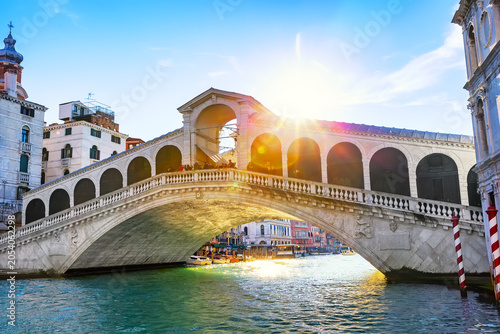 Historic Rialto Bridge illuminated by sunlight over the Grand Canal in Venice, Italy. One of the most photographed architectural landmarks in Europe.