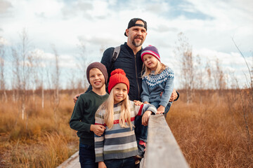 Father and family smiling on outdoor nature boardwalk in autumn