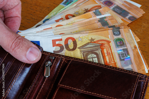 фотографія Hand taking a 50 Euro banknote from wallet, cost of living, wages, or inflation concept