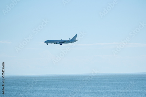 Passenger plane approaching airport over the sea on a sunny day