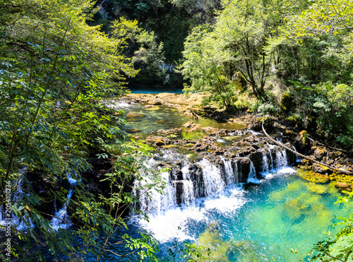 Fotografía Source of Una River waterfall with turquoise water and travertine cascades near