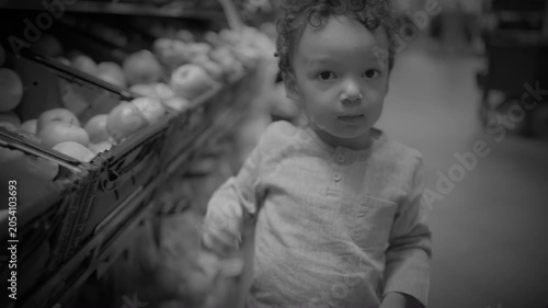 Toddler Reaching for Apples on a Grocery Produce Display