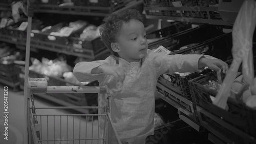 Child pushing small shopping cart in supermarket produce aisle