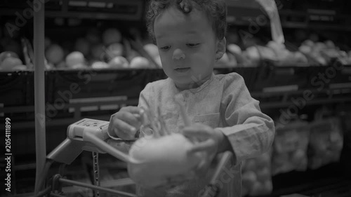 Child Sitting in Shopping Cart Holding Produce in Supermarket Aisle
