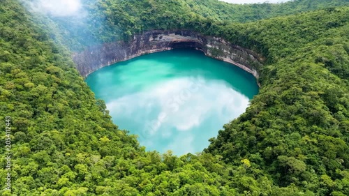 Aerial view of a beautiful turquoise volcanic crater lake surrounded by a lush green tropical forest