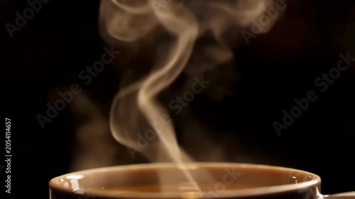Close up of hot steaming coffee in a mug on a dark background.