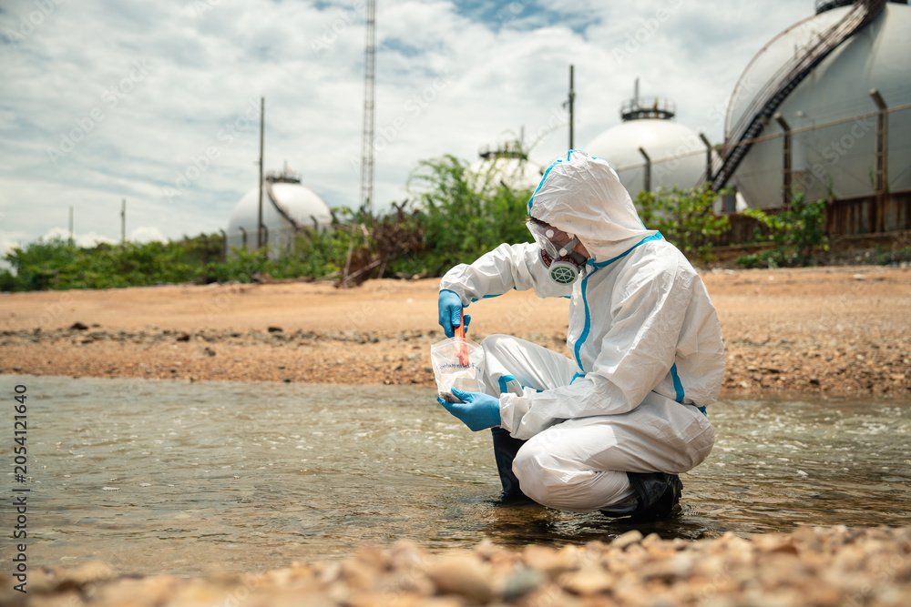 Obraz premium Industrial Pollution Inspector Gathering Wastewater Sample Near Refinery Drainage System For Environmental Investigation And Water Quality Assessment