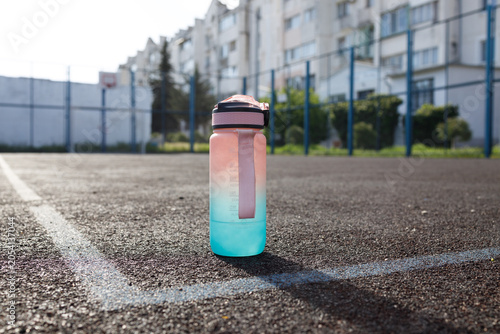 close up of sports water bottle on outdoor sports field showing hydration equipment and active lifestyle concept of fitness training athletics and sports equipment product