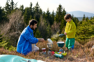 Father and son making coffee while camping