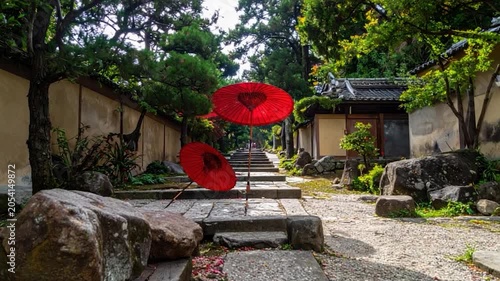 Japanese garden path with stone steps, red umbrellas, trees, and traditional buildings