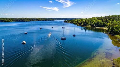 A vibrant aerial view of a lake with boats, jet ski, and lush green trees lining the shore