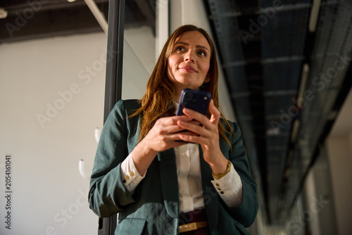 Beautiful woman holds a mobile phone inside the corporation