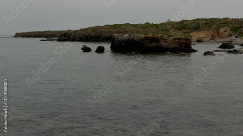Dark, rocky cliff jutting into the calm waters of the sea