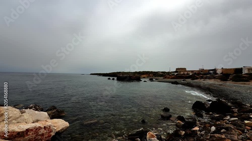 Calm sea and rocky headland under a thick, overcast sky