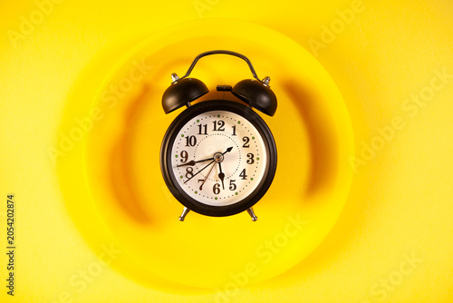Slika na platnu Retro alarm clock on yellow background. Top view with copy space
