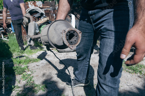 Bild auf Leinwand a man works at an old car junkyard