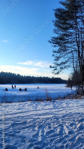 Beautiful winter landscape of a frozen lake covered in snow under a clear blue sky