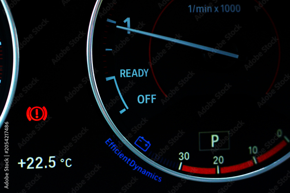 Fototapeta premium Car dashboard with illuminated warning indicators and tachometer.