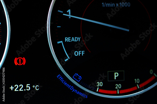 Car dashboard with illuminated warning indicators and tachometer.