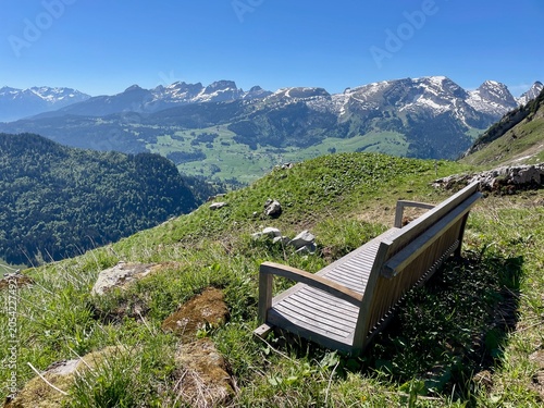 Wooden bench overlooking the panoramic view of the Churfirsten mountain range in the Swiss Alps, Toggenburg region, St. Gallen, Switzerland.