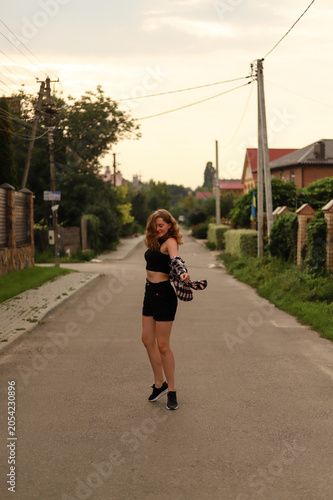 Joyful millennial girl enjoying a warm summer evening in a cozy neighborhood