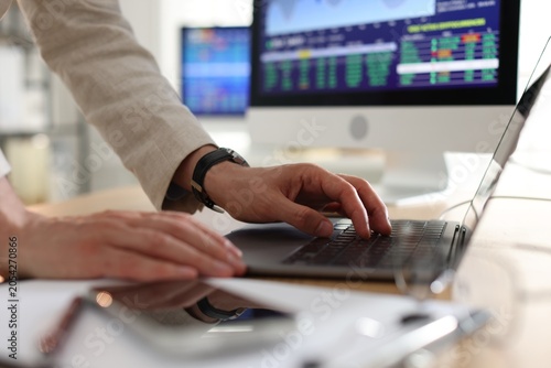 Quadro su tela Financial trading specialist working with laptop at desk in office, closeup