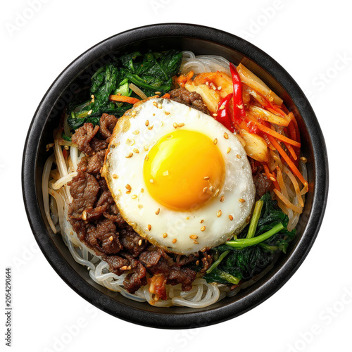Top view of delicious bibimbap bowl with fried egg beef spinach and spicy sauce overhead.