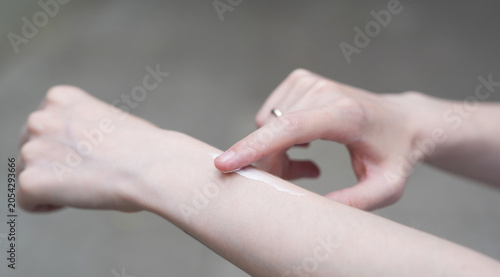 Schilderij op canvas hands of a woman applying white cream to the arm
