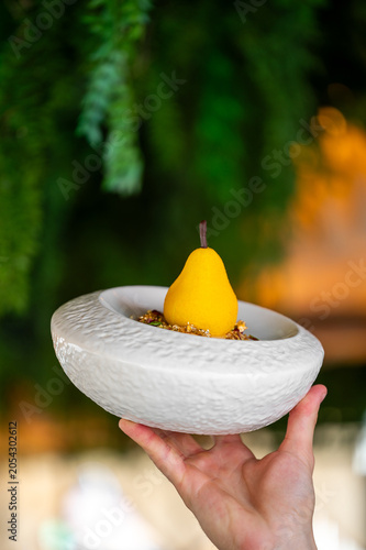 Quadro em tela A hand holds a textured white bowl featuring an elegant, pear-shaped gourmet des