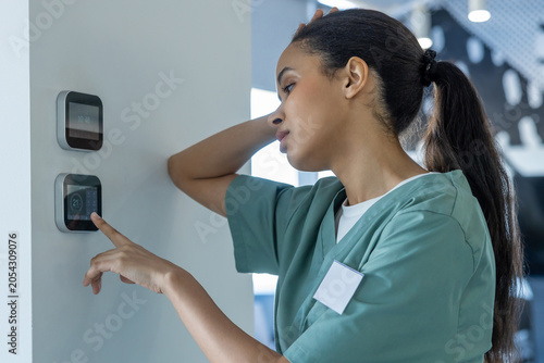Foto Tired after night shift doctor setting temperature on a climate control panel