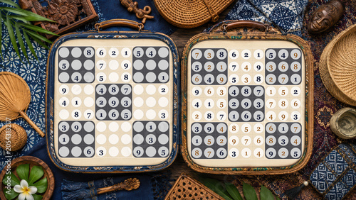 Tropical safari style rattan suitcases with sudoku games amid palm leaves and plumeria.