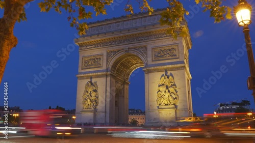 Arc de Triomphe in Paris, France with cars moving by quickly at night. 