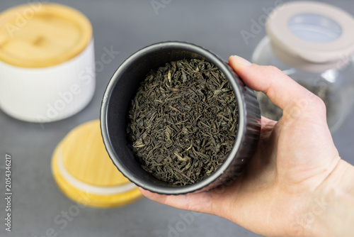 Black ceramic jar with black tea leaves. Close up.
