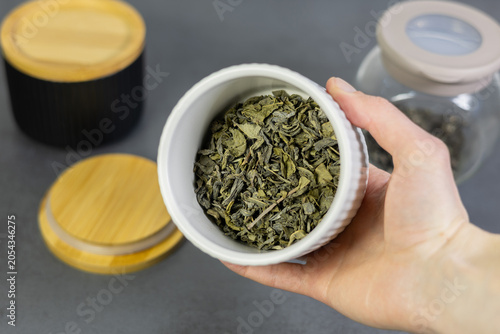 White ceramic jar with green tea leaves. Close up.