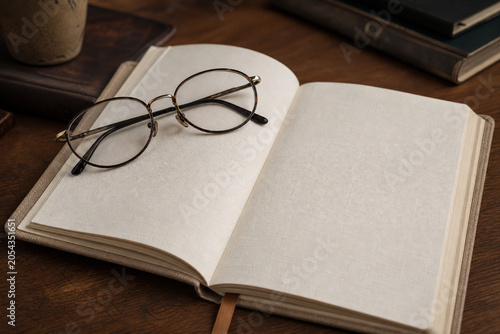 Open Notebook, Glasses, Blank Pages on Wooden Desk