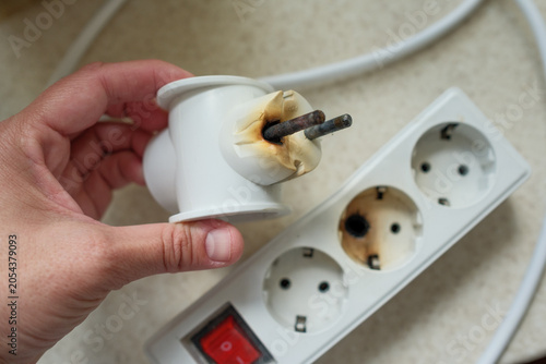 Fotografía Burned power strip and damaged electrical plug caused by overheating, short circuit, overload and fire hazard in home