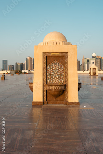 Fountain with mosaic tile art and a city skyline in the background.