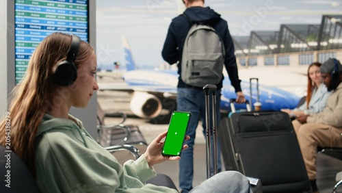 Tableau sur toile Vertical green screen on smartphone with girl digital nomad sitting in airport lounge, location independent young woman with freelance tasks, Work anywhere concept in the terminal with isolated