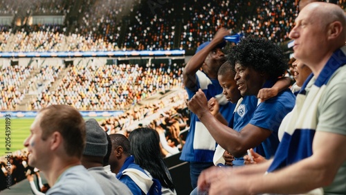 Принти на полотні Black father spending quality weekend time with son at packed soccer stadium full of cheering fans, football family lifestyle, parenthood and family bonding