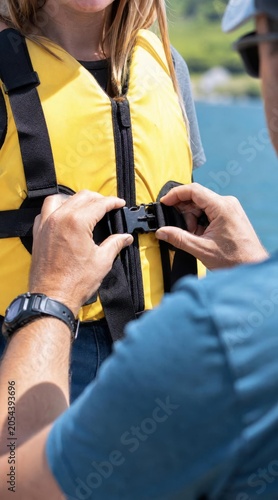 Guide securing life jacket on tourist