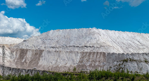 Huge white industrial hills under dramatic summer clouds in Lithuania