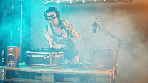 Cuadro en lienzo Musical specialist mixing records at turntables on stage, playing techno music at modern nightclub party